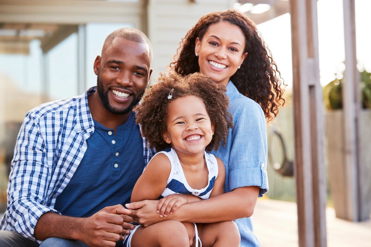 Family of three smiling outdoors, representing growth and connection through Crucible Therapy.